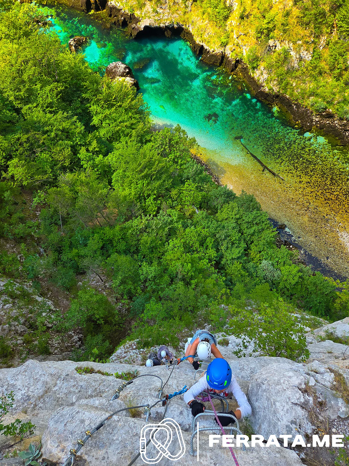 Looking down from the top of the wall at climbers below and the river far beneath them.