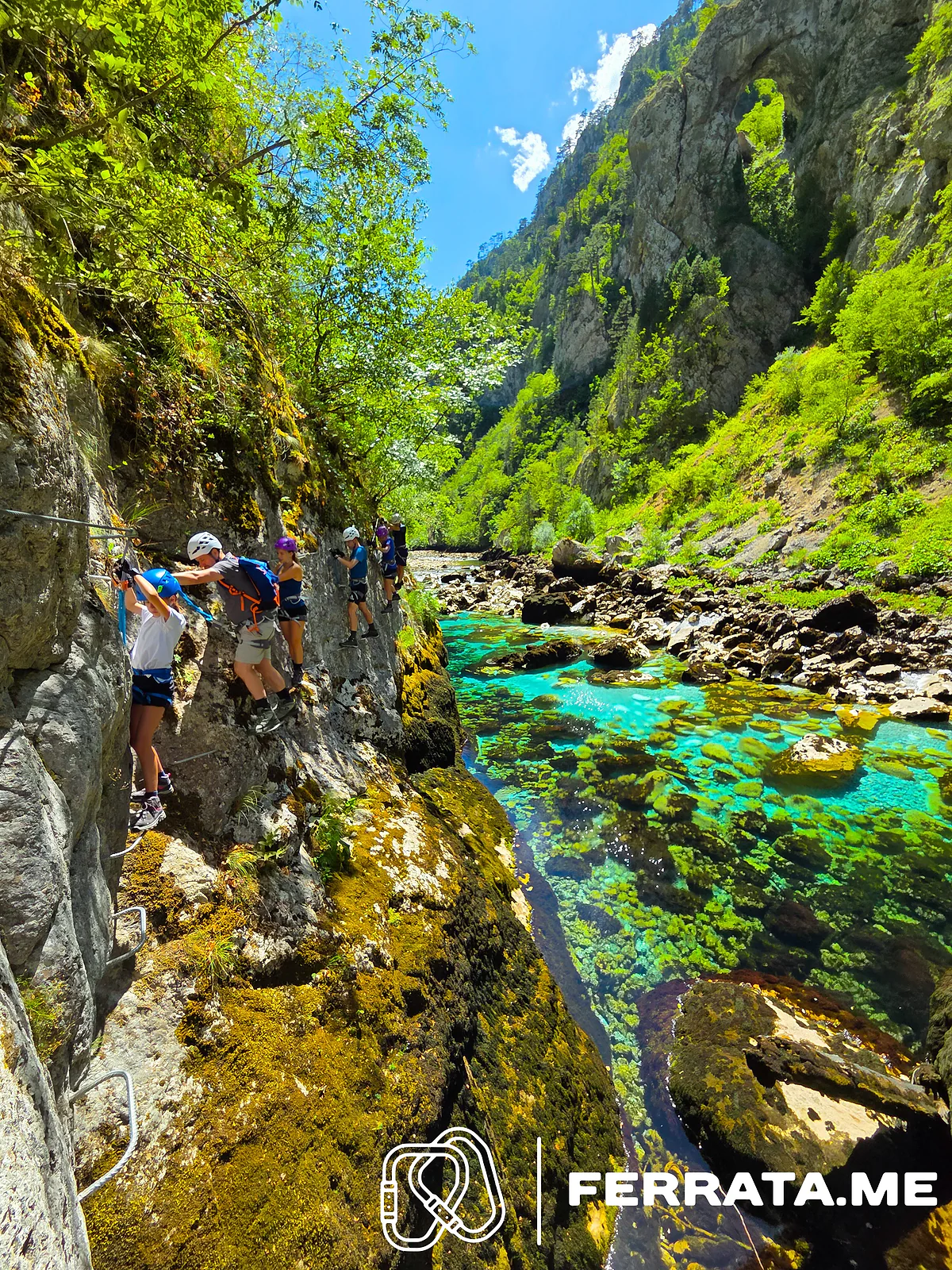A group on the traverse, moving along the cable beside the river.